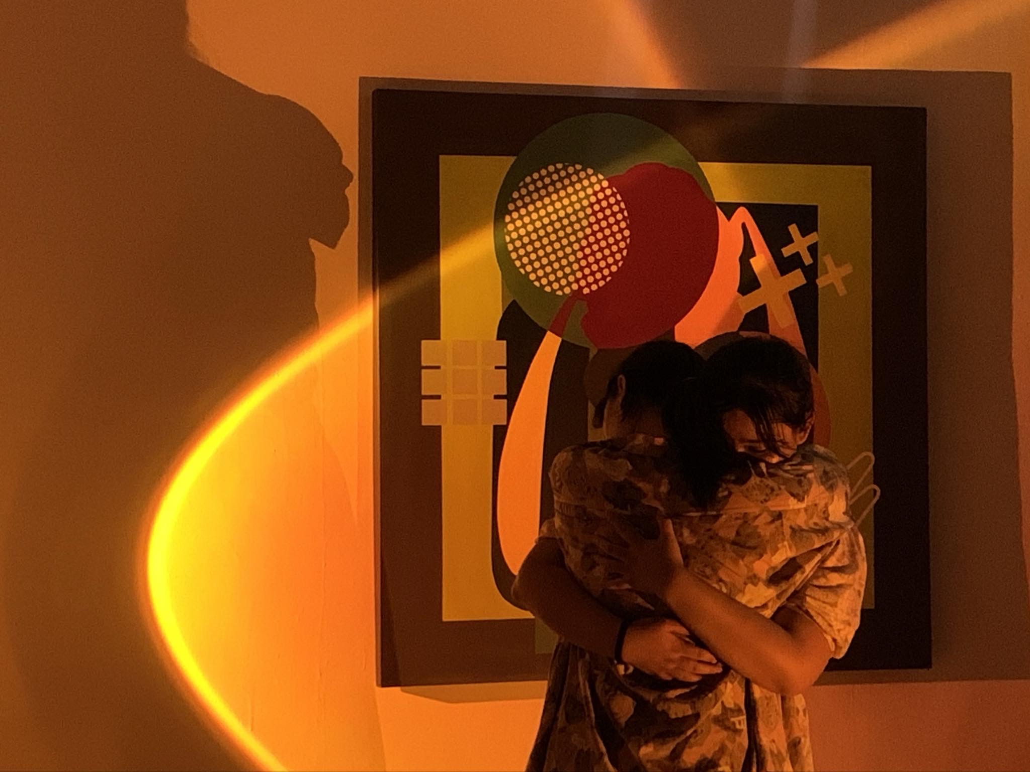 Performers embracing in the orange-lit set of (de)noise